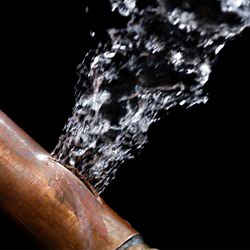 A bursting copper pipe in Napanee, with water gushing out.